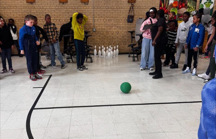  students gathered around makeshift bowling alley with anticipation